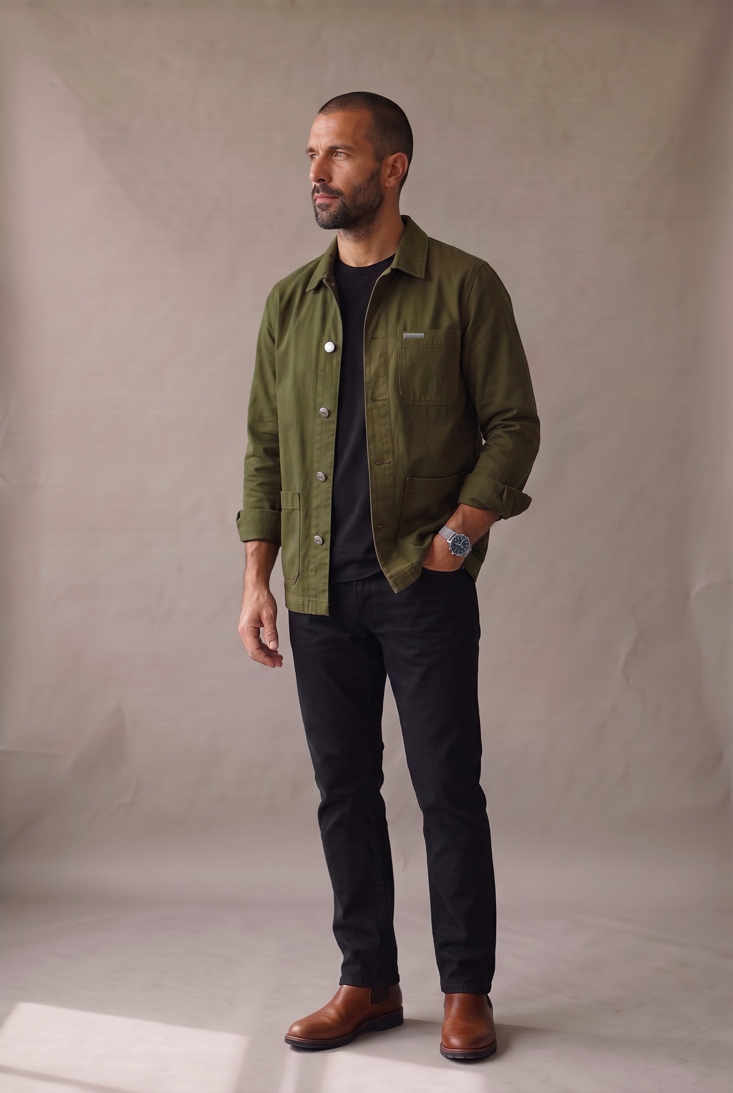 Chaqueta obrera verde militar para hombre de Luck & Load, vista lateral con las mangas arremangadas y botines chelsea de cuero café.