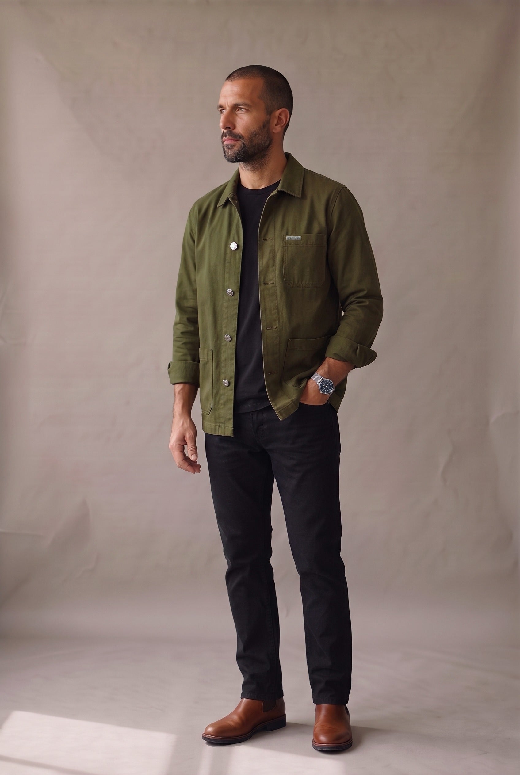 Chaqueta obrera verde militar para hombre de Luck & Load, vista lateral con las mangas arremangadas y botines chelsea de cuero café.