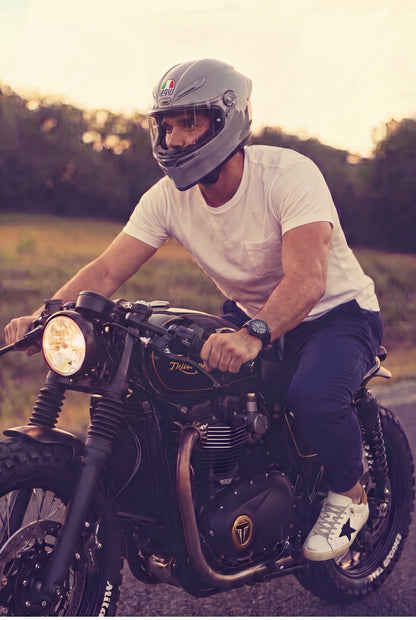 Hombre en jogger azul marino de Luck and Load con camiseta blanca, estilo de vida sobre moto cafe racer