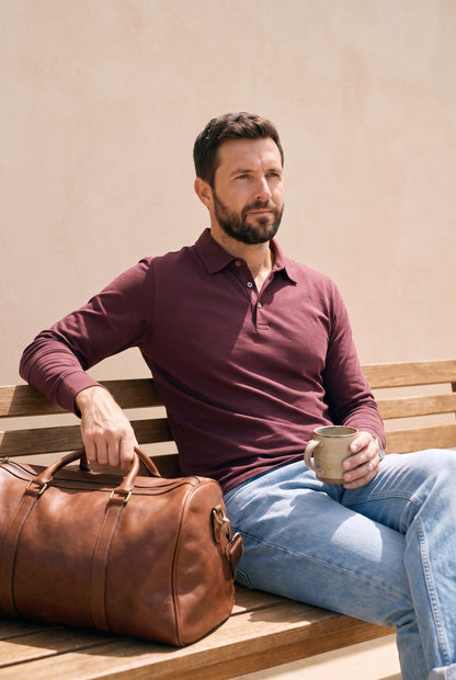 Hombre con polo de manga larga vinotinto de Luck & Load al aire libre en una terraza, foto de estilo de vida.